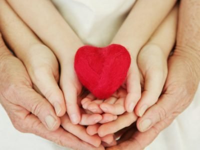 Three generations, child, mother and grandmother, holding a small felted heart.
